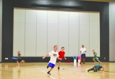 Students in Joe Garvin’s phy-ed class play a quick game of elephant tag so the guy from the newspaper can get a photo of students playing in the school’s new gymnasium. The game works like this: Players who are “it” try to tag players who aren’t with a section of a foam pool noodle resembling an elephant’s trunk. Once tagged, a player must do five push-ups before they are back in the game. One of the features of the room that Garvin and his colleague Kelly O’Laughlin plan to make use of this year is a retractable screen upon which they can project game rules and other information for their physical education students.